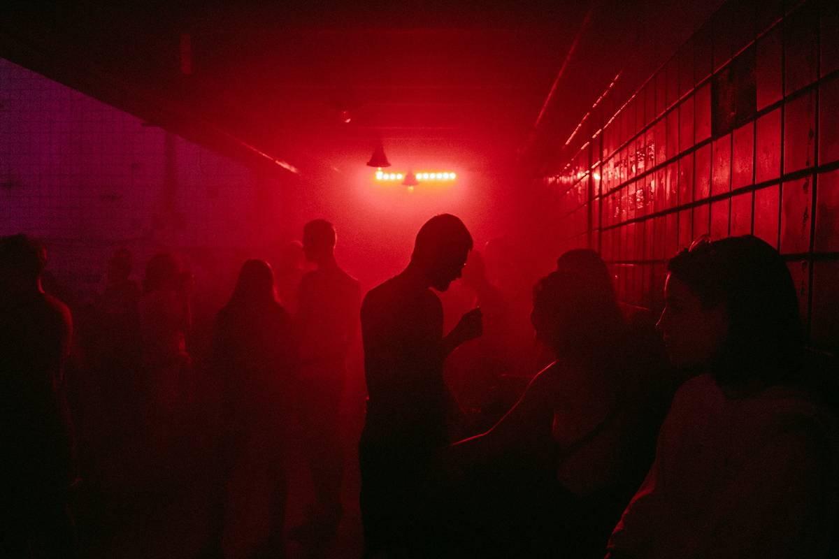 occult club investigation team using EMF meters and audio recorders in a dimly lit abandoned library